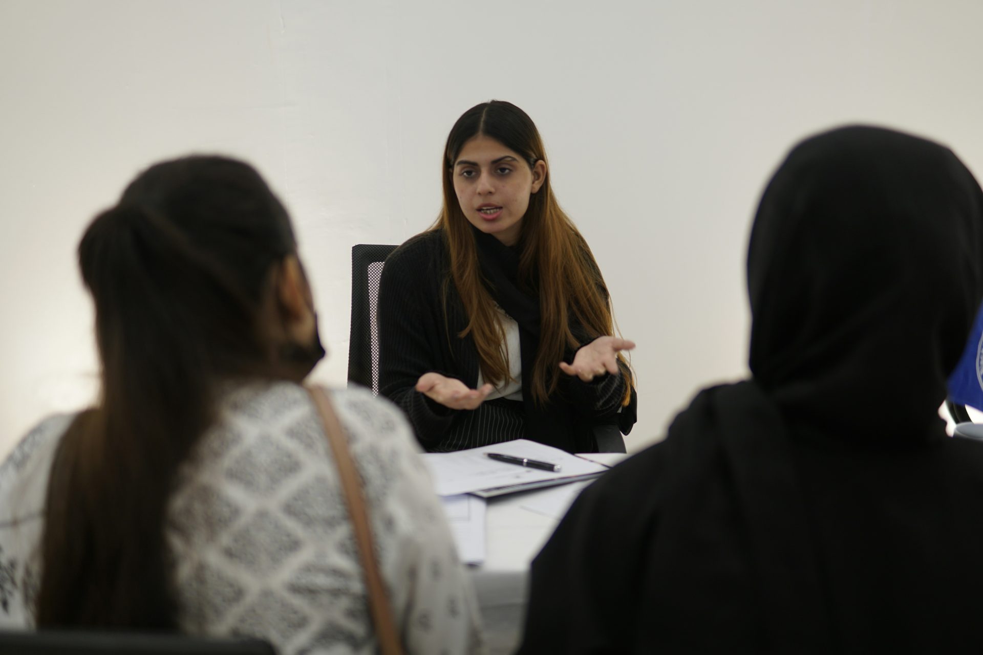 Eine Frau gestikuliert, während sie mit zwei Personen spricht.